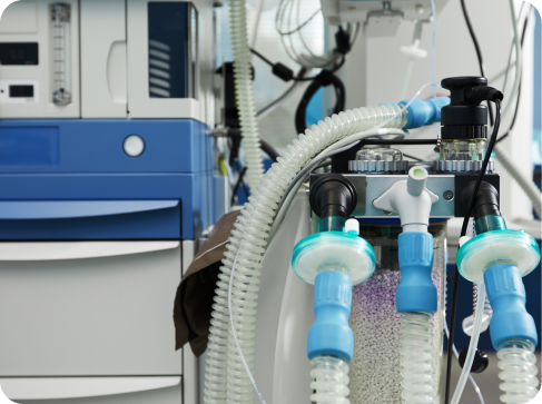 Close-up of a hospital ventilator machine with tubes and control knobs in a medical setting.