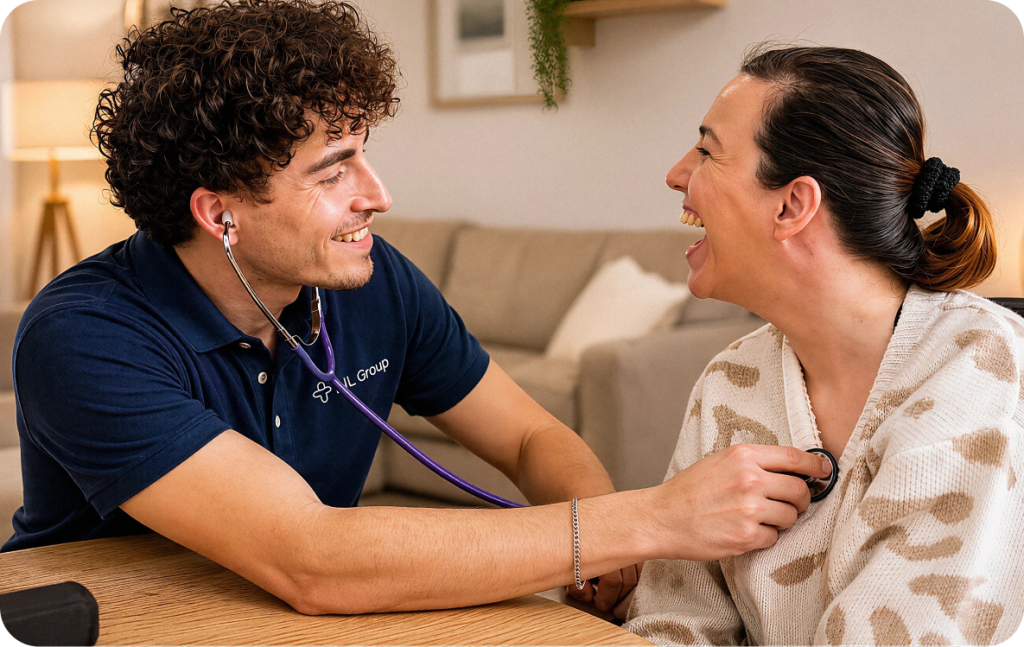 A healthcare professional uses a stethoscope to listen to a smiling woman’s chest in a home setting. Both appear engaged and comfortable during the checkup.